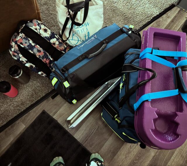 Midwives come with baggage. This midwife.....Six bags’ worth, to be exact.One backpack stuffed with procedures, protocols, the EHR laptop, and every form known to bureaucracy. One gifted “just in case” duffel—fresh scrubs, socks, and the sacred change of underwear so I can bounce birth-to-birth without smelling like yesterday’s miracle. One HUGE insulated lunch box layered like a hardy meats: breakfast burrito, lunch salad, leftovers, midnight PB&J, and enough snacks to outlast a 48-hour prodromal. One tote that’s 100 % Midwife Stephanie’s current knitting WIP (because idle hands finish baby hats). And then the three medical midwifery bags—the real cavalry.Here’s a Birds Eye view as we unpack those three: everything a CPM, LM drags through the door so physiologic birth stays sovereign and the rare emergencies stay solved.🩺 Full Resuscitation Station including emergency breathing support and infant epi.💉 Pharma & Fluids-Pitocin, Methergine, Misoprostol, TXA, vitamin K, & more.🪡 Suture & Repair- laceration tray, with lidocaine, and more.🫖 Herbs, Tinctures & Homeopathy-Shepherd’s purse, blue/black cohosh, motherwort, Arnica 200C, Rescue Remedy, Aconite, after-ease, cramp bark, and more.🌱 Oils & Comfort- Clary sage, lavender, frankincense, peppermint oils, hielicrysium, olive oil, and🧪 Labs & Monitoring-Doppler + gel, fetal stethoscope, BP cuff, pulse ox, urinary carbs, peri bottles and more.And the real MVP in every bag? My hands. They catch babies, map cervixes, guard perineums, calm mamas, and know when to pivot. All the gear is backup; skilled, present hands are the main event.Homebirth isn’t winging it—it’s meticulous prep meeting deep trust in birth.#HomebirthMidwife #CPM #BornAtHome #MidwiferyToday #HandsOnCare